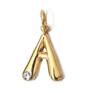 Macro detail view of gold-plated letter A pendant with a sparkling clear crystal