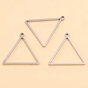 Gros plan de trois breloques triangulaires en acier inoxydable pour les bijoux DIY