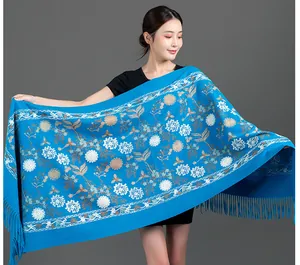 Detailed view of an elegant blue winter shawl featuring delicate floral embroidery and tassels