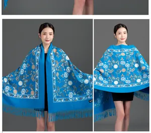 Detail view of blue embroidered floral scarf with fringe and cashmere-like texture.
