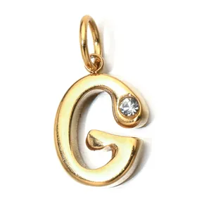 Macro view of gold stainless steel letter G pendant with inlaid clear stone