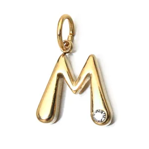 Detailed macro view of a gold-plated stainless steel letter M pendant with a crystal