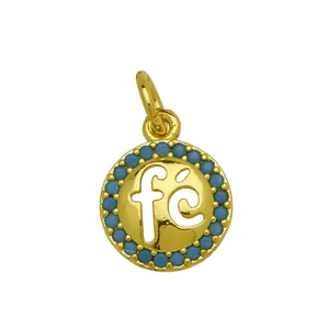 Detail view of 18K gold plated circular pendant featuring fé cutout and blue zircon border