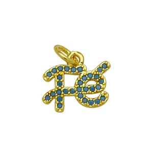 Detail of a 18K gold plated 'fé' faith pendant with inlaid blue cubic zirconia stones.