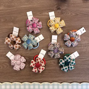 Sammlung bunter Blumen-Haargummis aus gepolstertem Stoff mit Blumen- und Punktmuster.