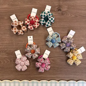 Detailansicht bunter gepolsterter Blumen-Haargummis aus Stoff mit Blumen- und Punktmuster.