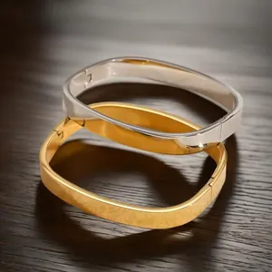 Vista dettagliata di bracciali rigidi quadrati minimalisti in finiture oro e argento lucido.