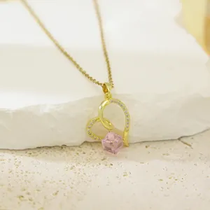 Detailed close-up view of a gold heart-shaped pendant set with a sparkling pink crystal
