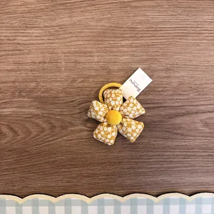 Nahaufnahme eines niedlichen gelben Stoffhaargummis mit Blumenmuster und weißem Etikett.