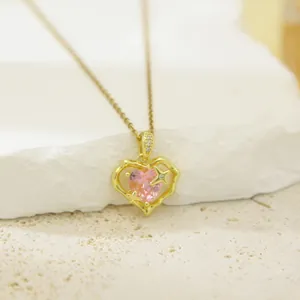 Elegant close-up of a gold heart pendant necklace featuring a pink crystal and star accents.