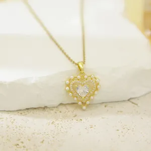 Elegant gold heart pendant necklace featuring central crystal and pearl border detail.
