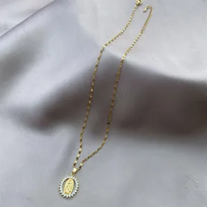 Detailed macro view of a gold Virgin Mary pendant necklace with sparkling zirconia stones