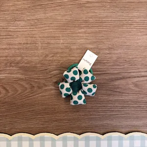 Nahaufnahme eines niedlichen grünen gepunkteten Haargummis mit Blumenmuster aus Stoff.