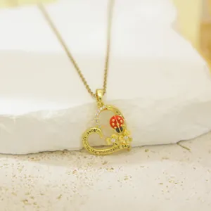 Close-up of golden heart pendant necklace with red ladybug and engraved love message