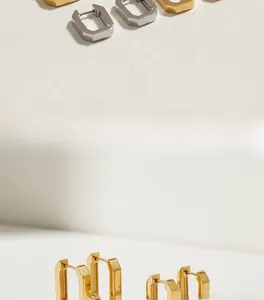 Detailaufnahme der glatt polierten Oberfläche minimalistischer goldener Rechteck-Ohrringe