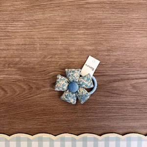 Detailansicht eines blauen Haargummis mit Stoffblumen auf einem Holzuntergrund.