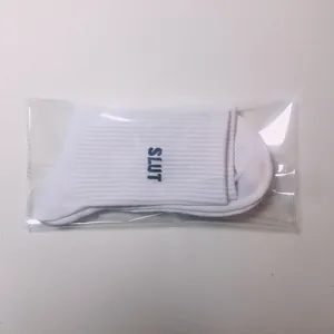Close-up of white ribbed cotton socks with SLUT letter embroidery in plastic packaging