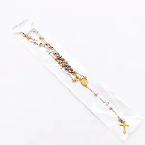 Close-up of a stainless steel rosary necklace featuring gold beads and a cross