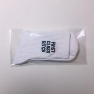 Detail shot of white cotton socks in plastic packaging with edgy blue letter print.