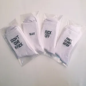 Detailed view of white cotton crew socks with bold black slogan embroidery designs