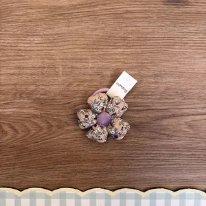 Nahaufnahme eines floralen Stoff-Haargummis für Mädchen auf einem Holzuntergrund