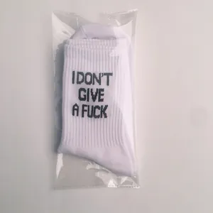 Detail view of white ribbed socks with 'I don't give a fuck' slogan in transparent bag