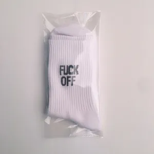 Detail view of white cotton socks with black FUCK OFF print in clear plastic bag
