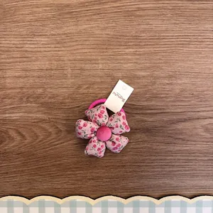Nahaufnahme eines rosa floralen Stoffhaargummis für Mädchen mit süßem Blumendesign