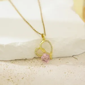 Elegant gold-plated heart pendant necklace with pink crystal stone on textured background
