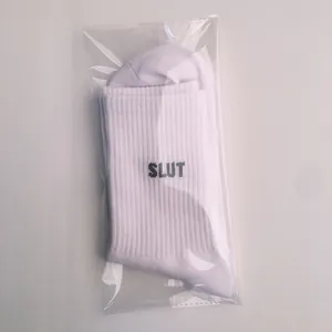 Detailed macro view of white ribbed cotton socks featuring black SLUT letter embroidery