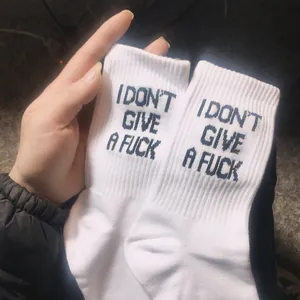 Detail of white cotton socks featuring bold "I DON'T GIVE A FUCK" slogan lettering.