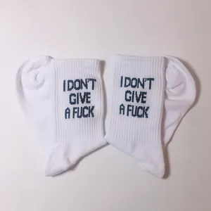 Close-up detail of white crew socks with dark blue I DON'T GIVE A FUCK slogan embroidery