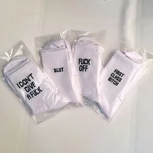 Detail view of four pairs of white cotton socks with bold English letter prints.