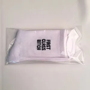Macro view of white cotton socks featuring black First Class Bitch bold text design