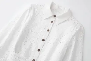 Détail d'une robe chemise blanche à manches longues avec broderie anglaise et boutons vintage