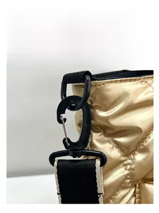 Close-up detail of golden quilted puffer tote bag showing black strap buckle and wide strap