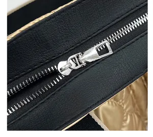 Close-up detail of smooth silver metal zipper on black quilted space cotton tote bag.
