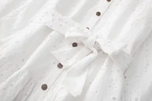 Détail de haute qualité d'une robe chemise blanche brodée avec nœud à la taille