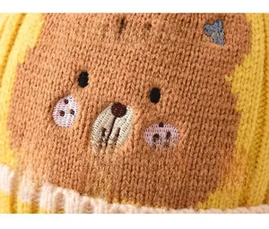 Nahaufnahme einer dicken Strickmütze für Babys mit süßem gesticktem Bärengesicht