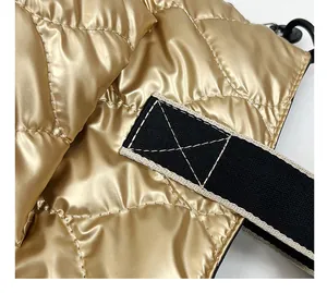 Close-up of golden quilted down cotton handbag showing metallic texture and strap detail