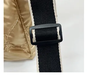 Macro view of adjustable black webbing shoulder strap on golden quilted space cotton bag