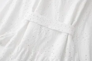 Détail de broderie anglaise blanche sur une robe chemise à manches longues