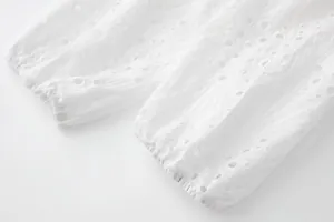 Détail en gros plan de la broderie anglaise blanche sur les poignets d'une robe
