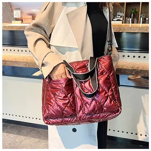 Close-up of a burgundy quilted padded tote bag with a striped wide shoulder strap.