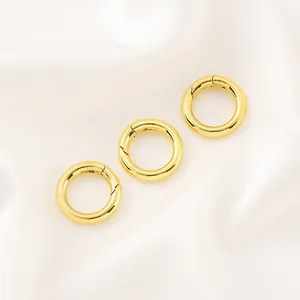 Détail de trois fermoirs à ressort circulaires plaqués or 14 carats sur fond de soie blanche