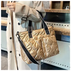 Stylish gold quilted down cotton tote bag with wide black shoulder strap shown on a model