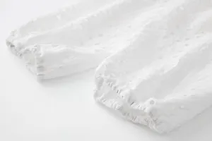 Vue macro détaillée du tissu brodé blanc et des poignets élastiques d'une robe chemise