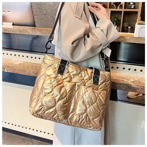 Large quilted metallic gold tote bag in space cotton with black wide shoulder strap.