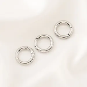 Lot de trois fermoirs à ressort circulaires argentés pour bijoux DIY sur satin blanc