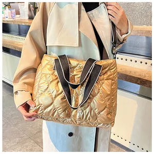 Close-up detail of a gold quilted puffer tote bag featuring striped wide shoulder straps